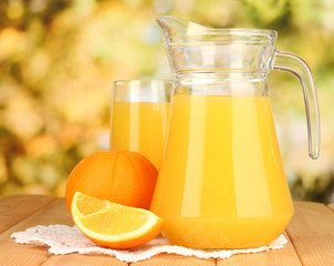 Full glass and jug of orange juice and oranges