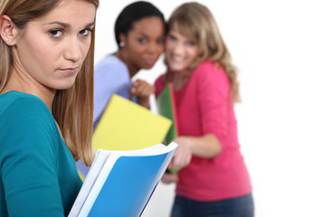 Two women with books making fun of a third woman