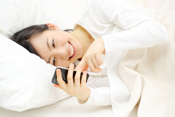 スマートフォンを寝ながら使う女の子