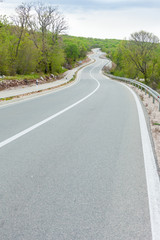 Curving black asphalt road with white marking lines from low poi