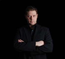 Portrait of man in black suit with crossed arms