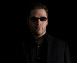 Fototapeta premium Portrait of man in black suit on black background