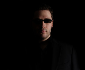 Naklejka premium Portrait of man in black suit on black background