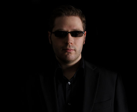 Portrait of man in black suit on black background