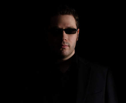 Portrait of man in black suit on black background