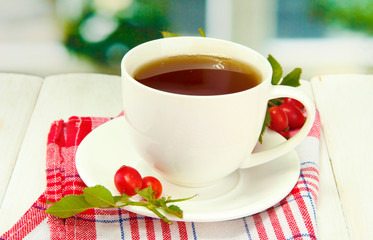 cup of tea with hip roses, on wooden table