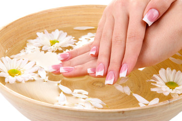 Obraz na płótnie Canvas Woman hands with french manicure and flowers in bamboo bowl