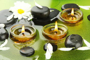 spa stones with flowers and candles in water on plate