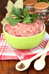 Bowl of raw ground meat with spices on wooden table