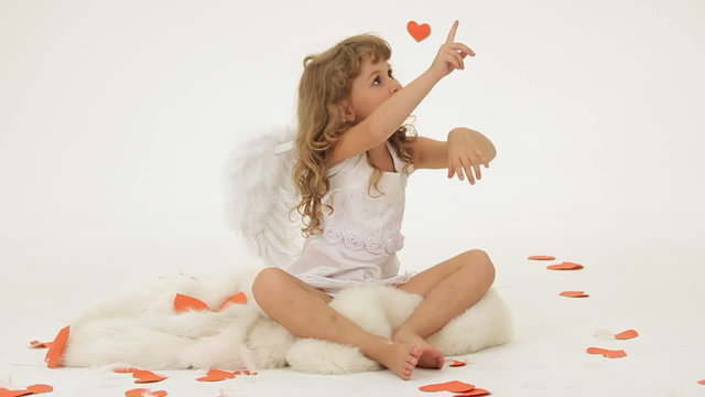 Little girl dressed as Cupid surrounded with paper hearts