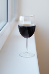 Glass with red wine on the windowsill