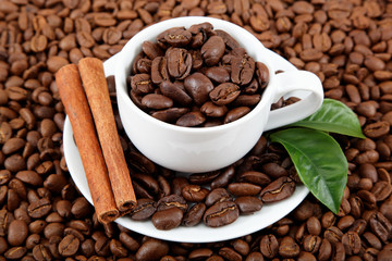 Cup with coffee beans and cinnamon sticks.