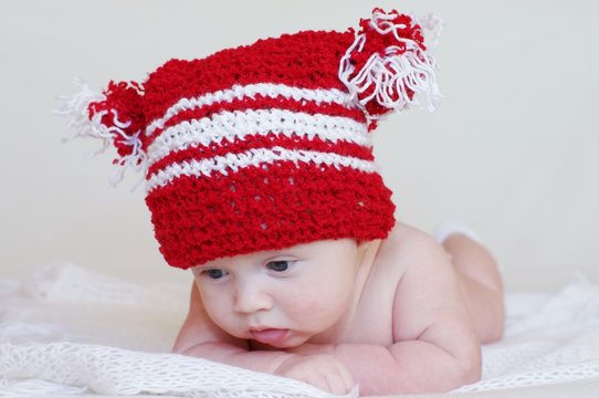 Portrait of the sad baby in a red knitted hat (3 months)