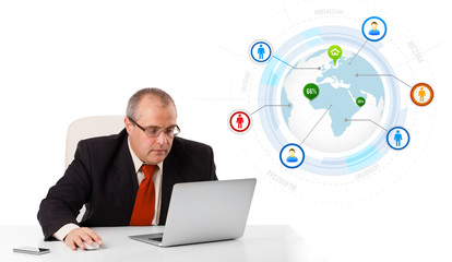 businessman sitting at desk and looking laptop with globe and so