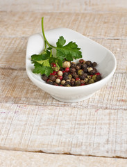 Mixed pepper in bowl on wooden background