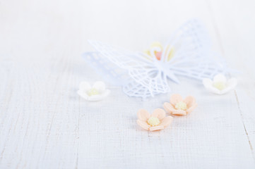 paper butterfly and three sugar blossom flowers on white old tab