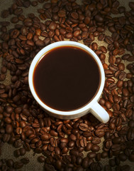 A cup of coffee and coffee beans on sacking