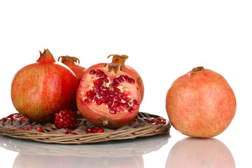 Ripe pomegranates on wicker cradle isolated on white