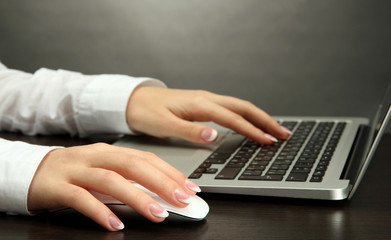 female hands writing on laptot, on grey background