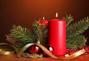 Two candles and christmas decorations, on brown background