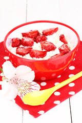 Cottage cheese in red bowl with sliced strawberries