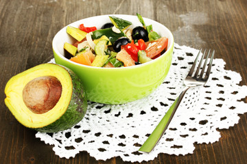 Tasty avocado salad in bowl  on wooden table close-up