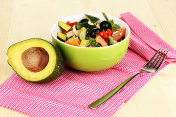 Tasty avocado salad in bowl  on wooden table close-up