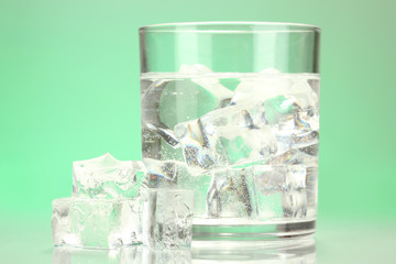 Ice cubes in glass on light green background