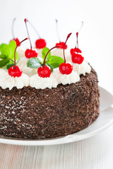 Chocolate cake with whipped cream and glazed cherries