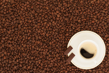 cup of coffee with chocolate pieces on coffee beans background