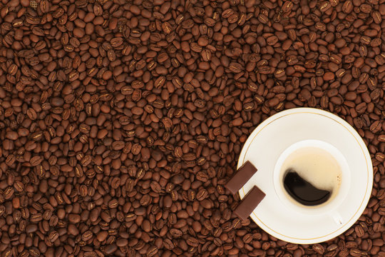 cup of coffee with chocolate pieces on coffee beans background © GLandStudio