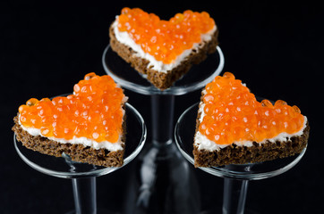 three sandwich with red caviar in the form of a heart