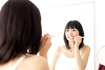 attractive asian woman brushing teeth
