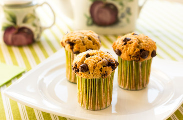 Chocolate chip muffins on white plate and green striped tableclo