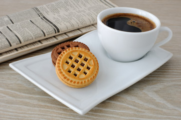 A cup of coffee and biscuits and a newspaper