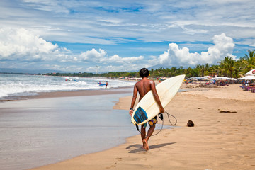 Young man with surf board on beach in Bali, Indonesia. © Aleksandar Todorovic