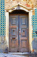 Old wooden door in Portugal. Wall of  tiles
