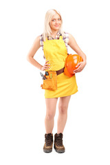 Smiling female worker with a tool belt holding helmet