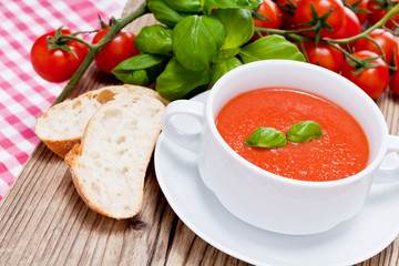 Frische tomatensuppe in einer weißen suppentasse mit basilikum