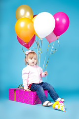 Fototapeta na wymiar Beautiful little girl with balloons and gift celebrating