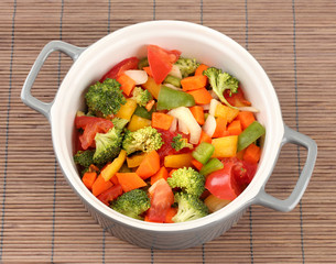 Vegetable stew in gray pot on bamboo mat background