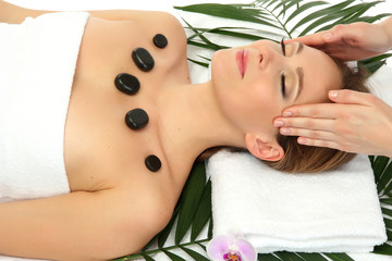 Portrait of beautiful woman with spa stones taking head massage