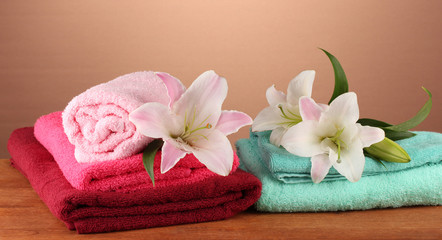Fototapeta na wymiar stos ręczniki z różowego lily na brązowym tle