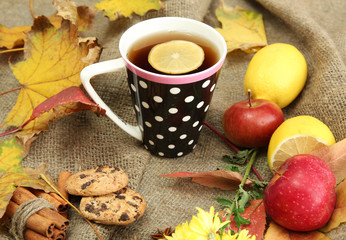 cup of hot tea and autumn leaves, on burlap background