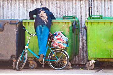Poor woman searching in garbage