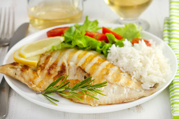 grilled fish with boiled rice and salad on the plate