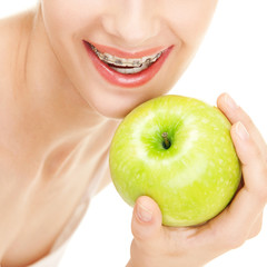 Girl in braces with green apple on white background