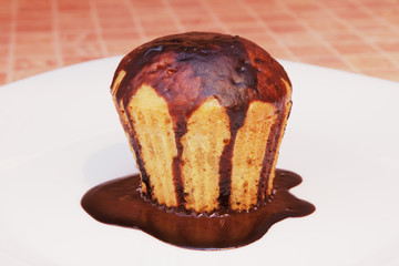 Homemade cupcake with chocolate on white plate.