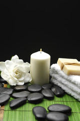 Fototapeta na wymiar Gardenia i kamienie z mydła na ręcznik i świeca na macie zielonego