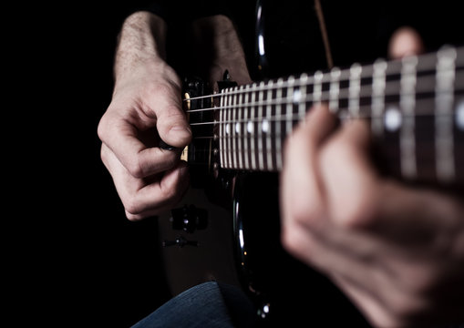 Human hand playing an electric guitar